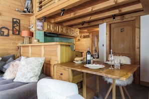 L’intérieur chaleureux d’un chalet avec une table à manger en bois, un canapé et un coin cuisine.