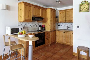 Una cocina funcional con armarios de madera, un microondas, una estufa y un lavamanos.