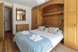 A bedroom with a bed, a dresser, a mirror, and wooden doors. - Residence des Alpes 302, Skiing, Chamonix All year (Chamonix)