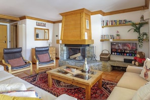 A cozy living room with a fireplace, leather chairs, a coffee table, and a television. - Residence des Alpes 302, Skiing, Chamonix All year (Chamonix)