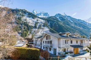 Un hôtel de style chalet doté d’un balcon, situé dans un cadre magnifique, avec des montagnes enneigées en toile de fond.