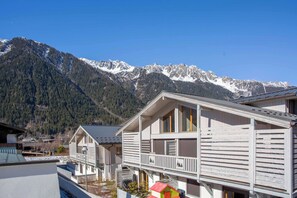 Un chalet de montagne doté d’un balcon, entouré de sommets enneigés.