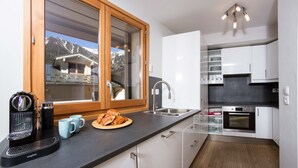 Ett modernt kök med ett stort fönster, en kaffemaskin och en tallrik med mat.