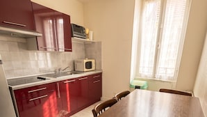 Una cocina con una mesa de comedor y sillas, un microondas y una ventana con cortinas.