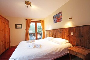 Een slaapkamer met een groot bed, een houten hoofdbord en een raam met gordijnen.
