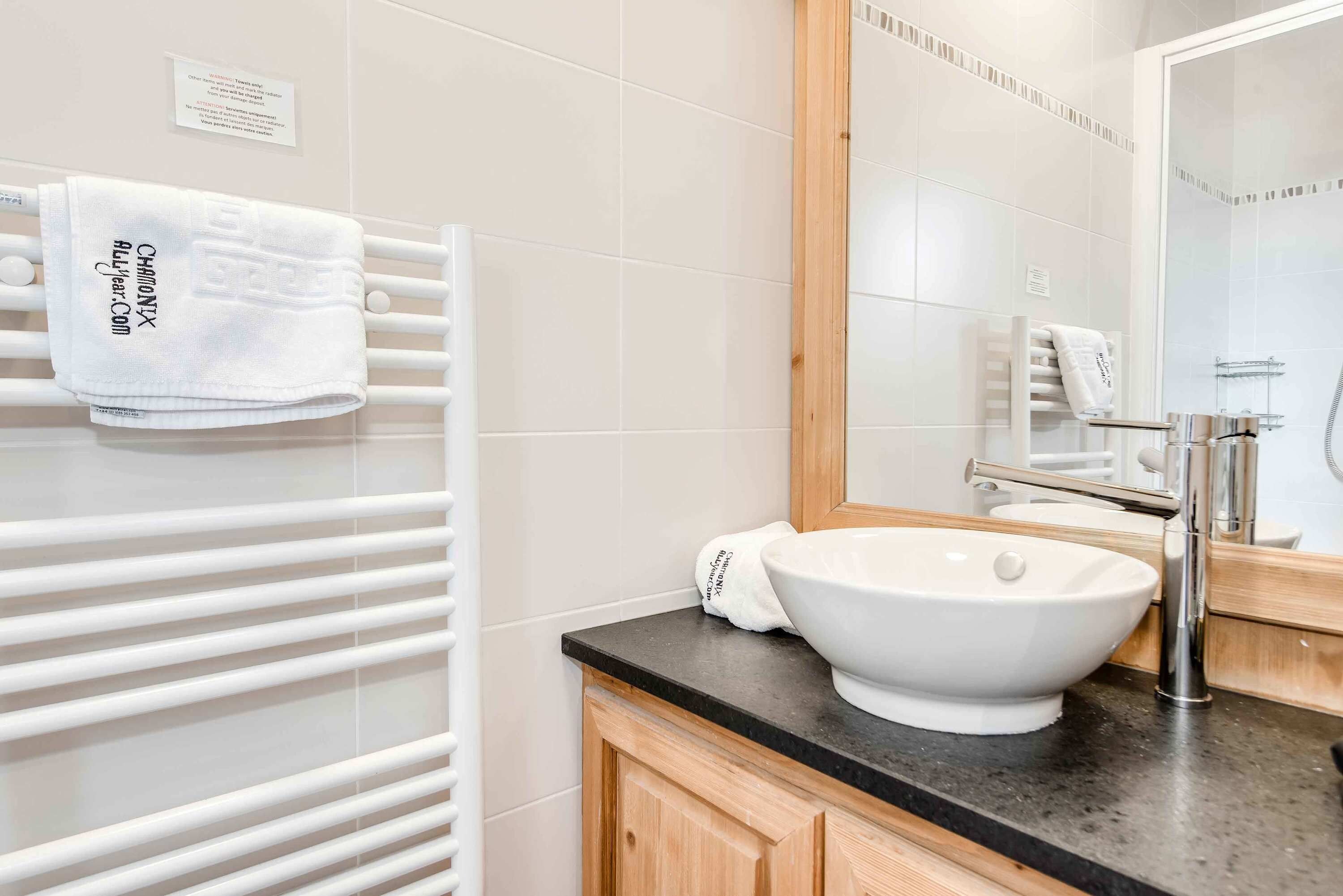 Un baño moderno con un toallero blanco, un lavabo blanco y un espejo encima.