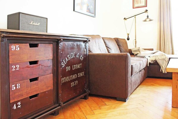 A vintage wooden chest with numbered compartments, a brown sofa, a lamp, and a framed picture on the wall.
