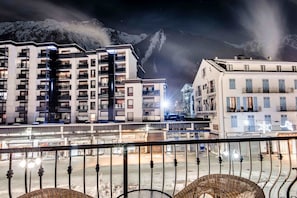 Un hôtel moderne à plusieurs étages, doté de balcons et offrant une vue sur des montagnes enneigées.