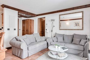 A living room with two grey sofas, a white coffee table, a floor lamp, and a large mirror on the wall.