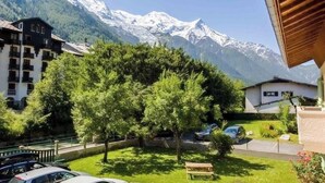 Vue d’une station de montagne avec des sommets enneigés, un parking et un bâtiment doté de balcons.