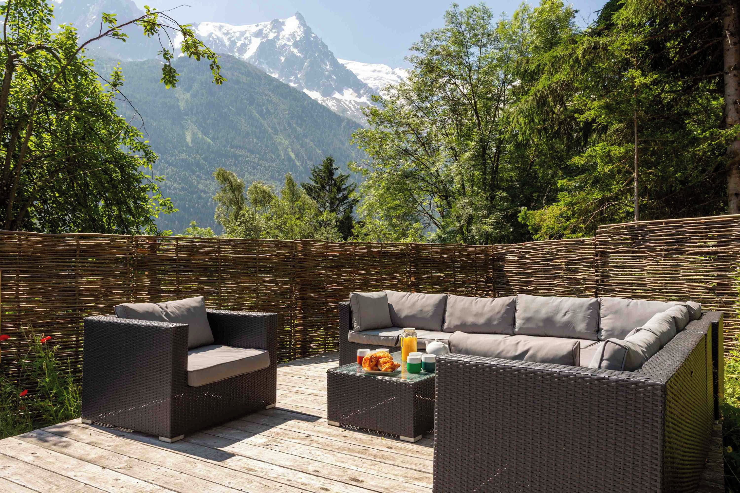 A wicker outdoor seating area with a view of a mountain.