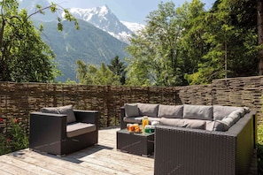 Un espacio de estar al aire libre con muebles de mimbre y vistas a la montaña.