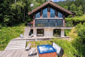 A modern two-story house with a wooden deck, a hot tub, and a satellite dish. - Ski Chalet La Source with hot tub (Chamonix)