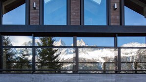 Un edificio moderno con amplios ventanales que ofrecen vistas a montañas nevadas y una zona boscosa.