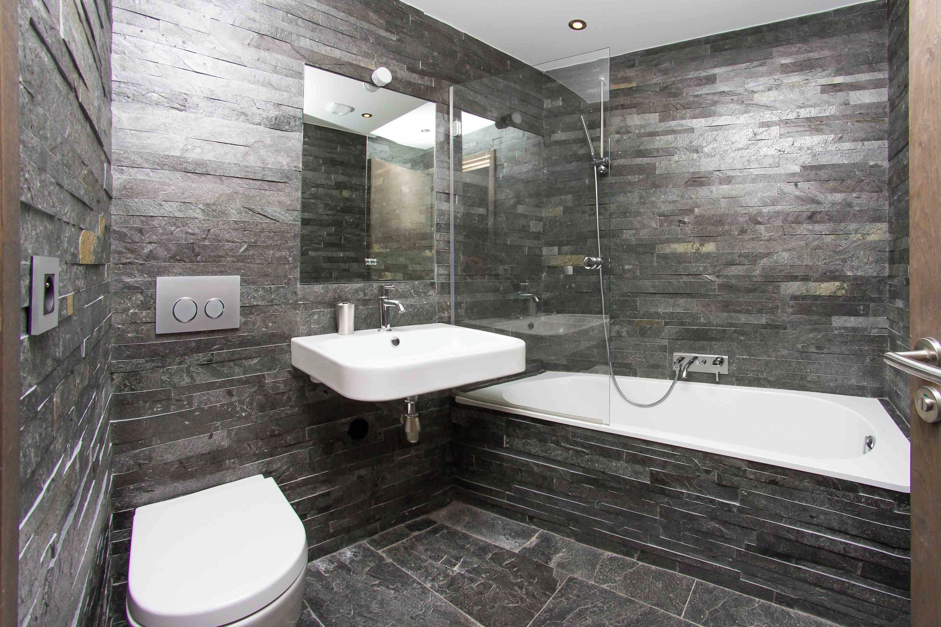 A modern bathroom with a white toilet, a sink, and a bathtub.