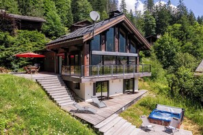 Une cabane moderne à deux étages, dotée d’une terrasse en bois, d’un jacuzzi et d’une antenne parabolique.