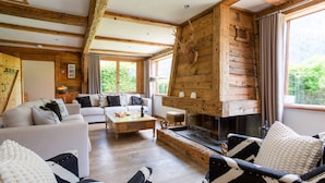 A cozy living room with a fireplace, wooden walls, and comfortable seating.