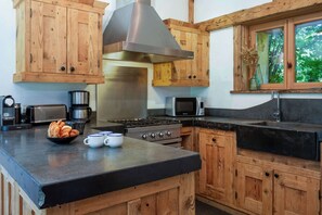 A kitchen with wooden cabinets, a stainless steel range hood, a microwave, and a coffee maker.