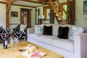 Un salon chaleureux avec un canapé, une table basse sur laquelle sont disposés des plats et des boissons, et un plafond en bois.