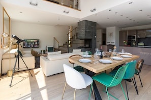 A modern kitchen with a built-in oven, a dining area with a wooden table and chairs, and a staircase leading to an upper level. - Luxe Chalet Couttet - skiing - Chamonix All Year (Chamonix)