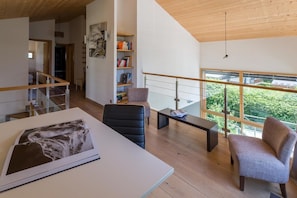 Een modern interieur met een trap, een eethoek en een uitzicht door grote ramen.
