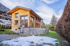 A modern wooden house with a stone foundation, large windows, and a stone staircase leading to the entrance. - Luxe Chalet Couttet - skiing - Chamonix All Year (Chamonix)
