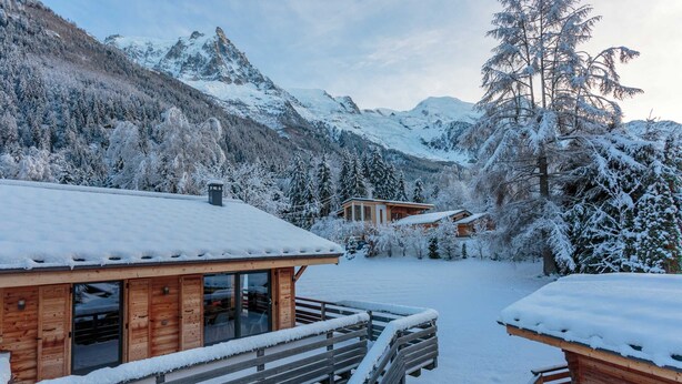 Een houten chalet met balkon, omringd door met sneeuw bedekte bomen en bergen.