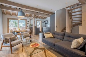 Un soggiorno moderno con un divano, poltrone, un tavolino in vetro e un'area pranzo con tavolo e sedie.
