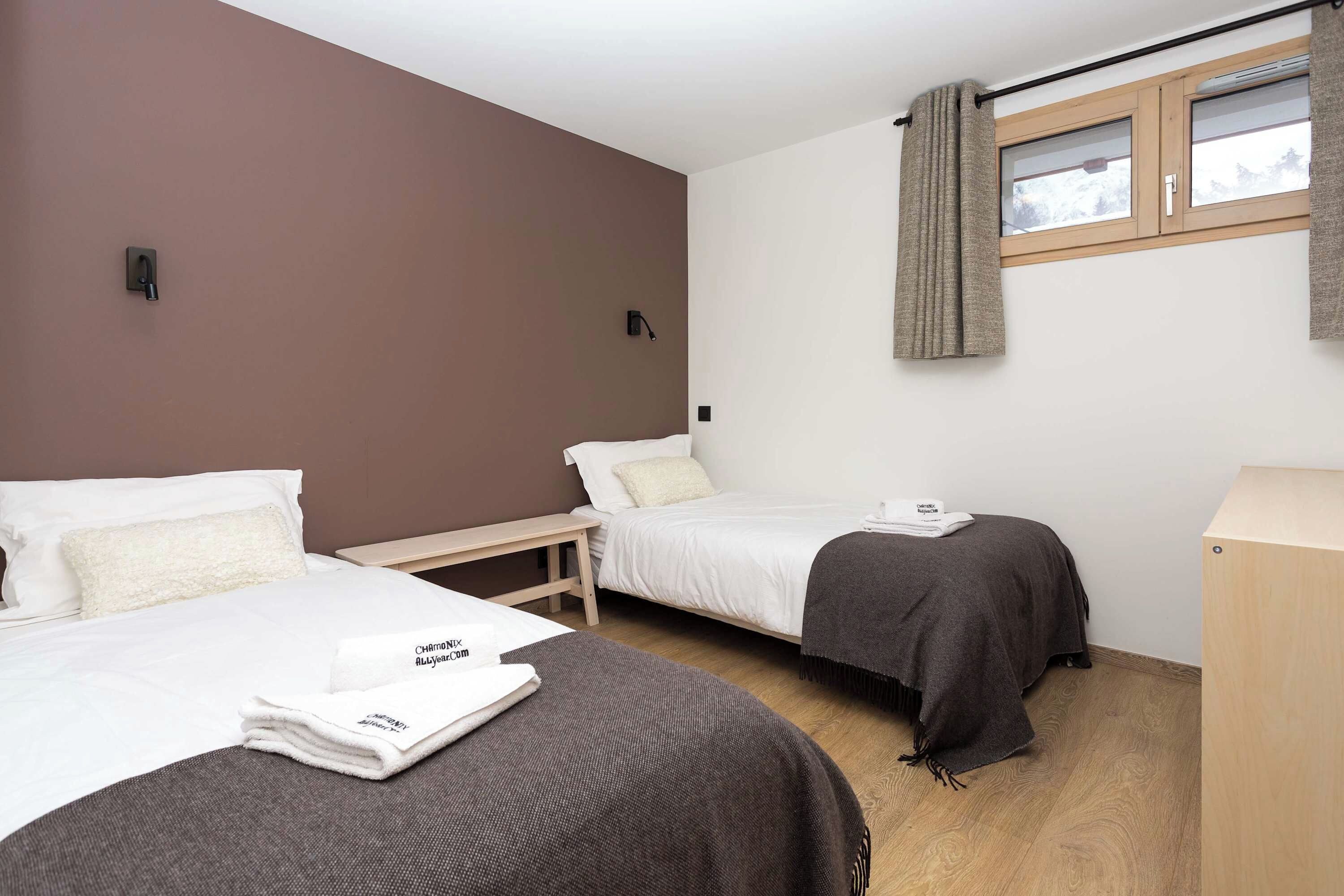 Ein Hotelzimmer mit zwei Betten, einem Nachttisch aus Holz, einem Schreibtisch und einem Kleiderschrank.