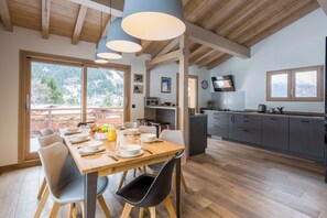 Una cucina moderna con zona pranzo, travi in legno e vista sulle montagne.