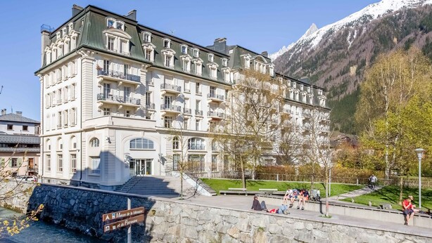 A historic hotel with a stone facade, multiple balconies, and a view of a mountain. - Mont Blanc 212 Apartment -  an apartment that sleeps 2/4 guests  in 1 bedroom (Chamonix)
