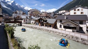 A river with a raft and a bridge in a town with buildings and mountains in the background. - Mont Blanc 212 Apartment -  an apartment that sleeps 2/4 guests  in 1 bedroom (Chamonix)