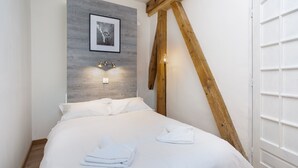 A neatly made bed with white linens and towels, a framed picture on the wall, and a wooden beam structure. - Mont Blanc 212 Apartment -  an apartment that sleeps 2/4 guests  in 1 bedroom (Chamonix)