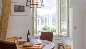 A dining table with a view of mountains and buildings through a window. - Mont Blanc 212 Apartment -  an apartment that sleeps 2/4 guests  in 1 bedroom (Chamonix)