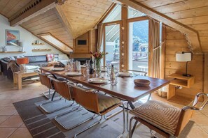 A cozy dining area with a long wooden table set for four, surrounded by leather chairs.