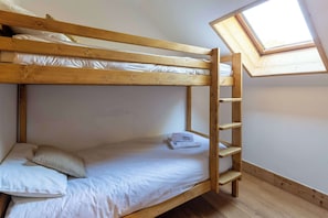 Een stapelbed met dakraam, houten ladder en kussens.