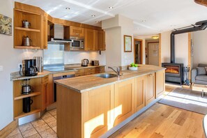 Eine moderne Küche mit Holzschränken, einem Edelstahlherd und einem eingebauten Backofen.