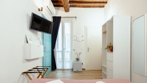Une chambre à coucher avec un lit, une télévision, une armoire et une petite table sur laquelle est posée une plante.