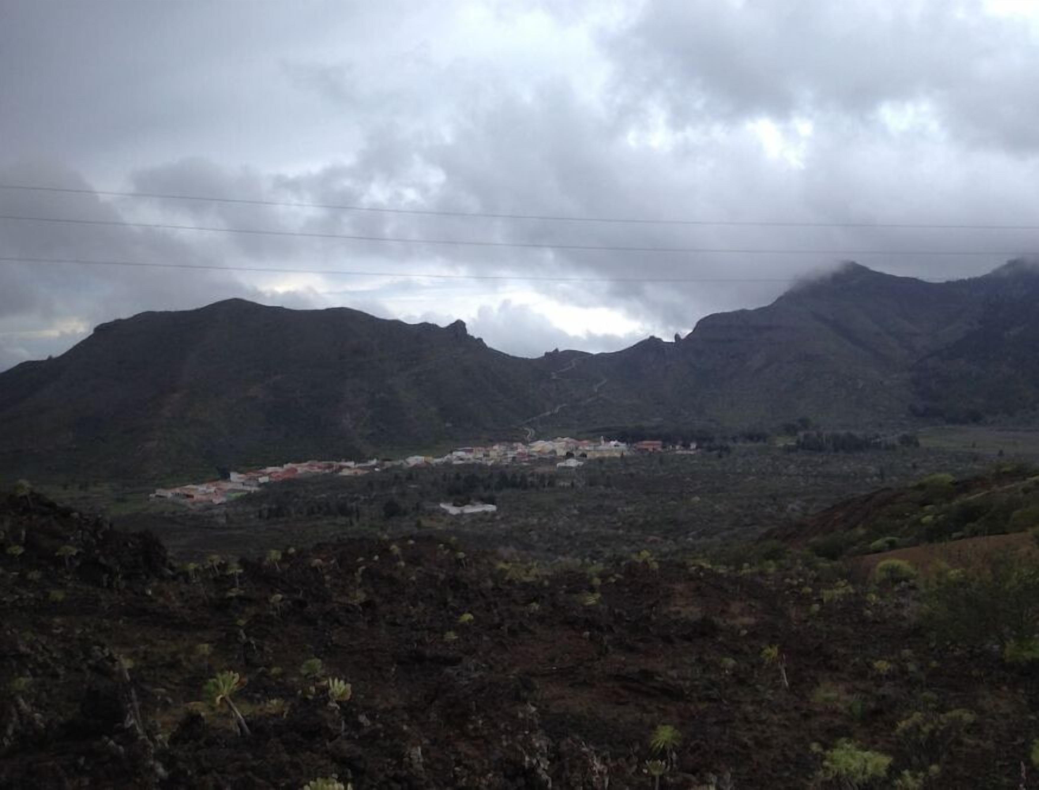 Un paisaje montañoso con un pequeño asentamiento en el valle.