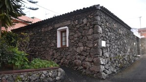 A stone building with a small window and a stone wall.