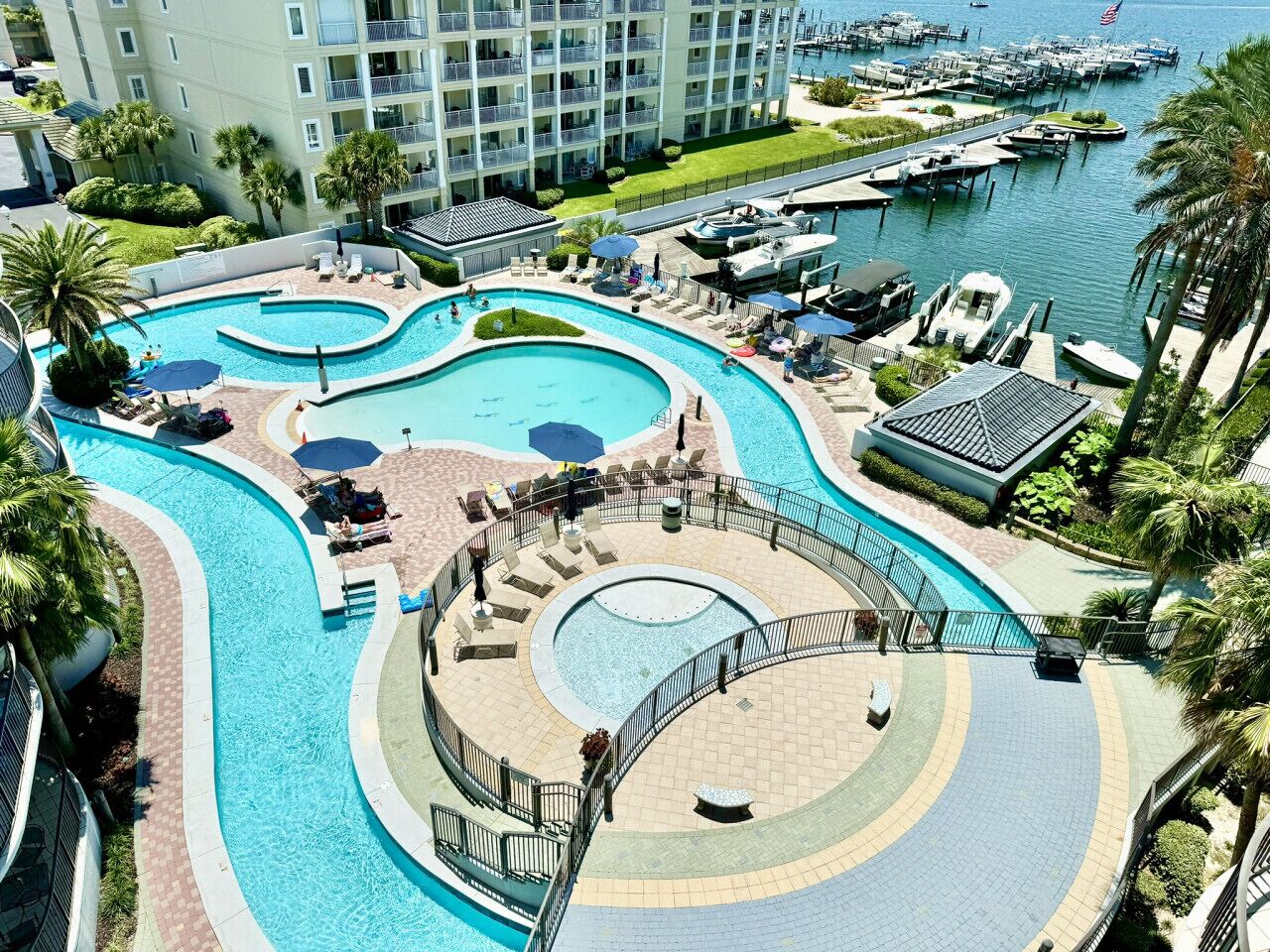 A resort with multiple swimming pools, a marina, and a large building with balconies.