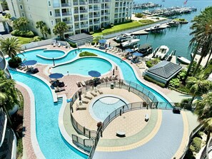 A resort with multiple swimming pools, a marina, and a large building with balconies.