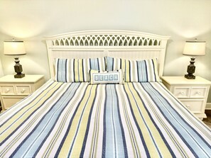 A bed with a striped bedspread, two pillows, and a headboard with a lattice design.