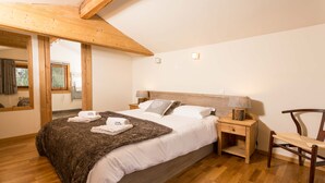Une chambre à coucher avec un lit en bois, une table de chevet, une chaise et une fenêtre avec des rideaux.