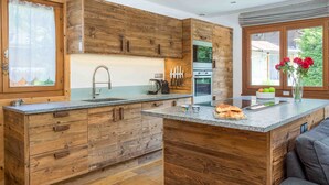 Une cuisine moderne avec des meubles en bois, un plan de travail en granit et un four encastré.