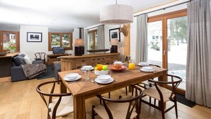 Un coin repas avec une table en bois, des chaises et un téléviseur en arrière-plan.
