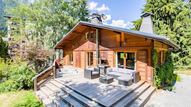 Une cabane en bois dotée d’une terrasse, d’un espace salon extérieur et d’un jacuzzi.