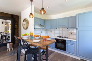 A modern kitchen with blue cabinets, a wooden dining table, and a gas stove. - La Saleina Apartment, Skiing, Chamonix All Year (Chamonix)