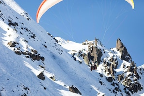 A snowy mountain landscape with rocky outcrops and clear skies.