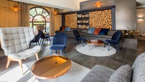 A modern living room with a sofa, chairs, a coffee table, and a bookshelf.